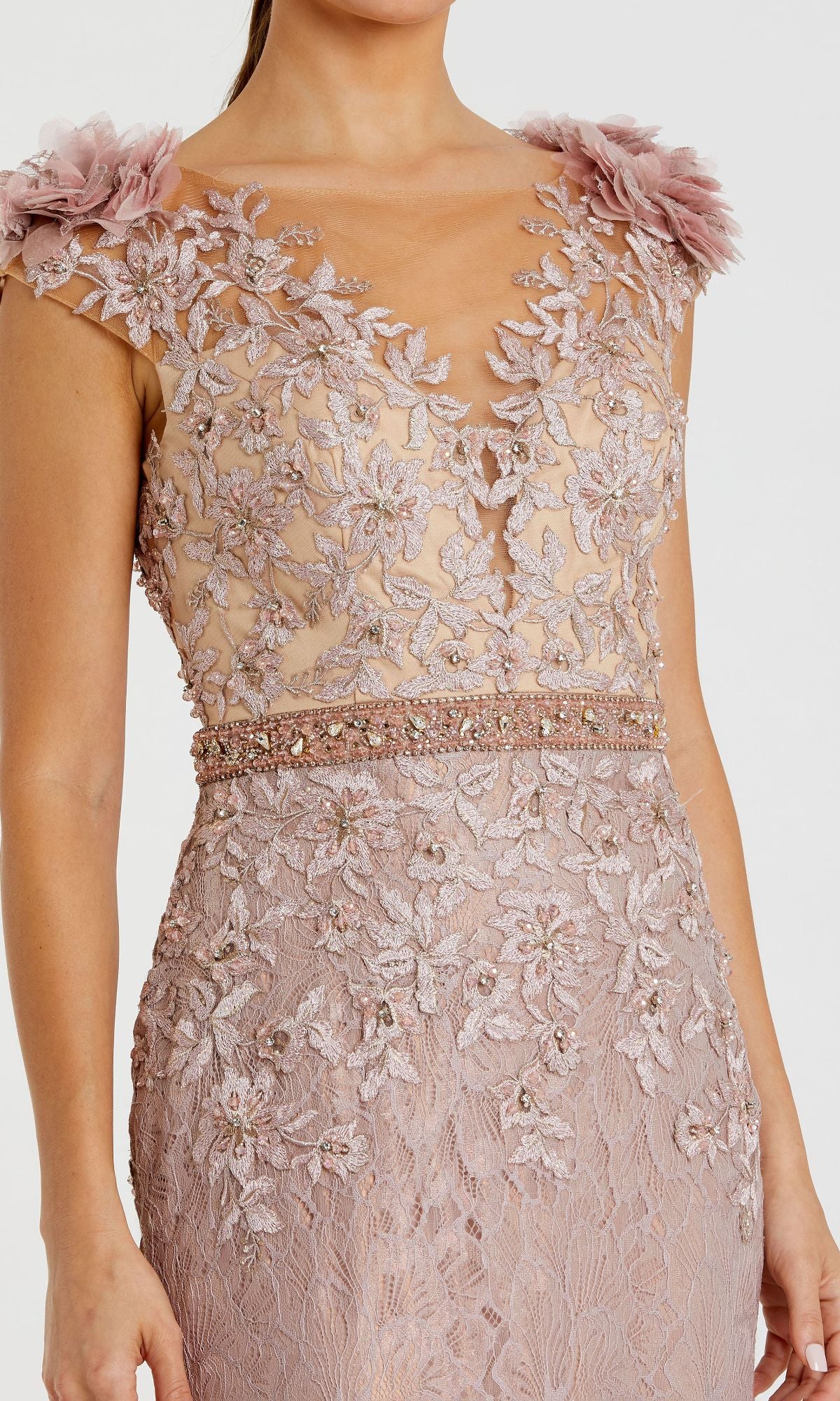 Woman wearing the Cap-Sleeve Long Formal Dress Mac Duggal 79368 in blush pink, featuring floral lace embroidery, a sheer bodice, beaded waistline, and 3D floral appliqués on the shoulders.